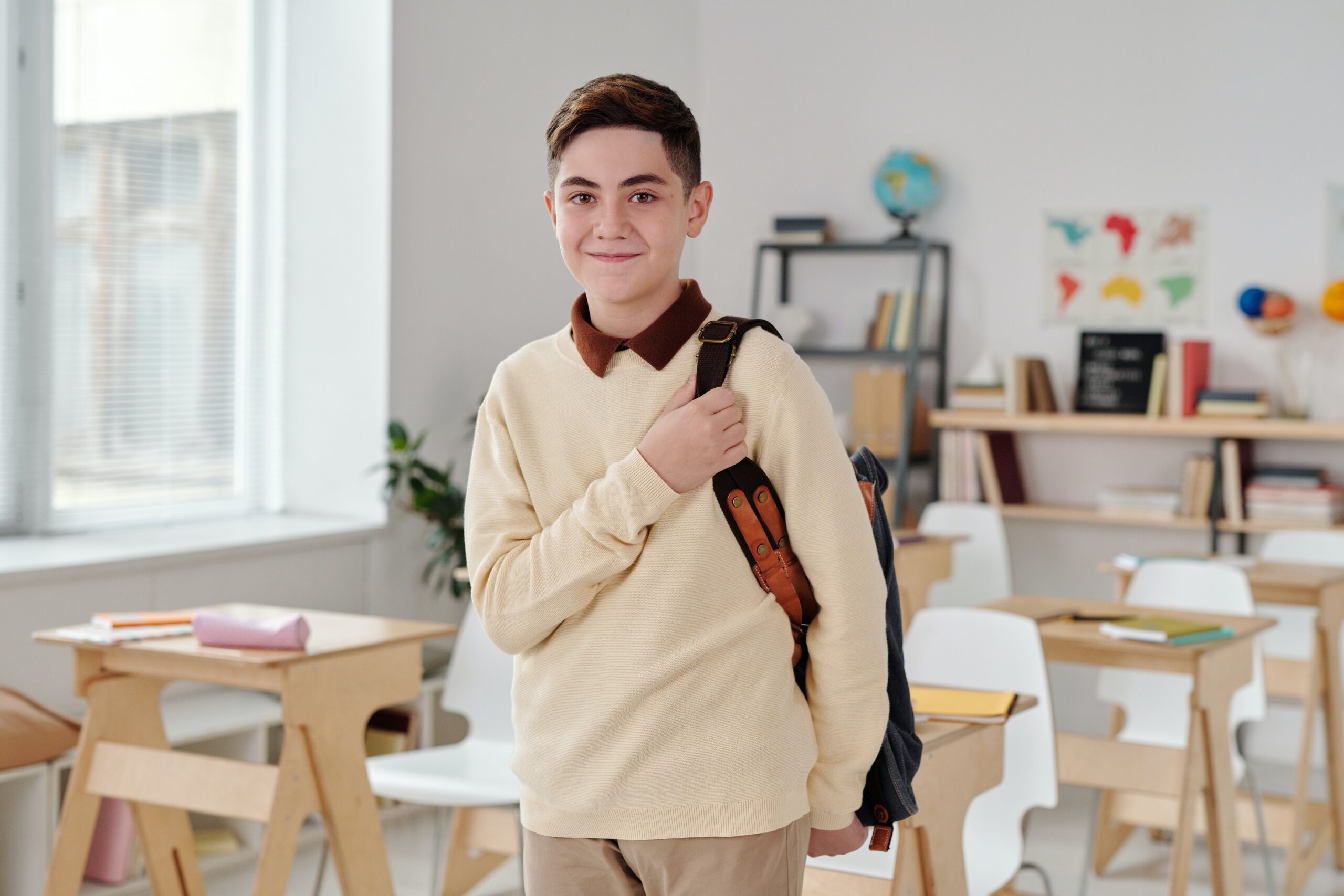 Niño con una mochila en una clase sonriendo.